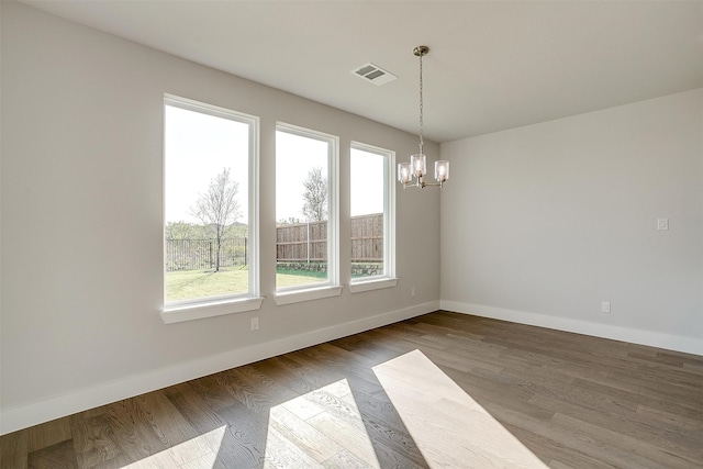 unfurnished dining area featuring wood-type flooring and an inviting chandelier