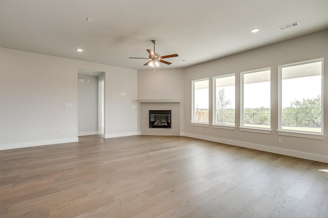 unfurnished living room with ceiling fan, light hardwood / wood-style flooring, and a fireplace