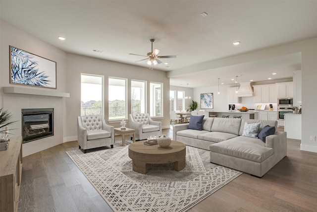 living room featuring light hardwood / wood-style flooring, a tile fireplace, and ceiling fan