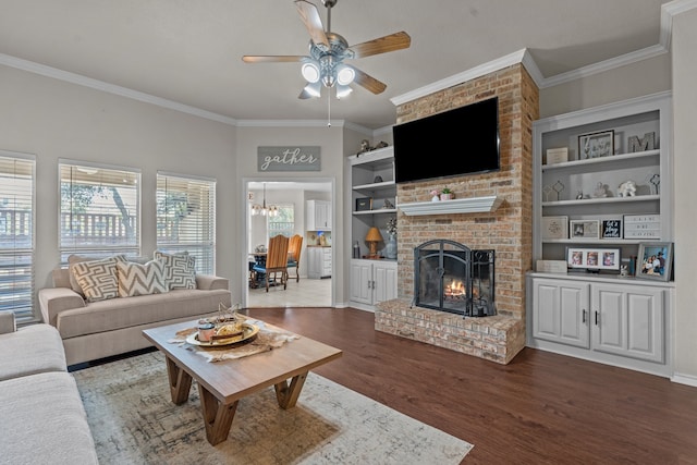 living room featuring a fireplace, ceiling fan with notable chandelier, ornamental molding, built in features, and hardwood / wood-style floors