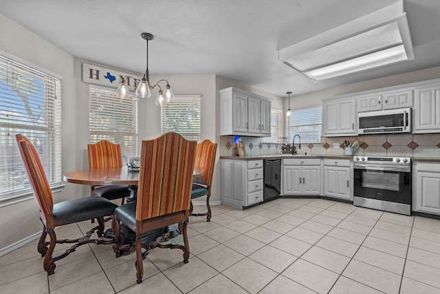 kitchen with stainless steel appliances, backsplash, light tile patterned flooring, sink, and a chandelier