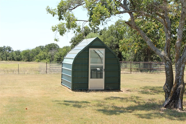 view of outdoor structure featuring a lawn and a rural view