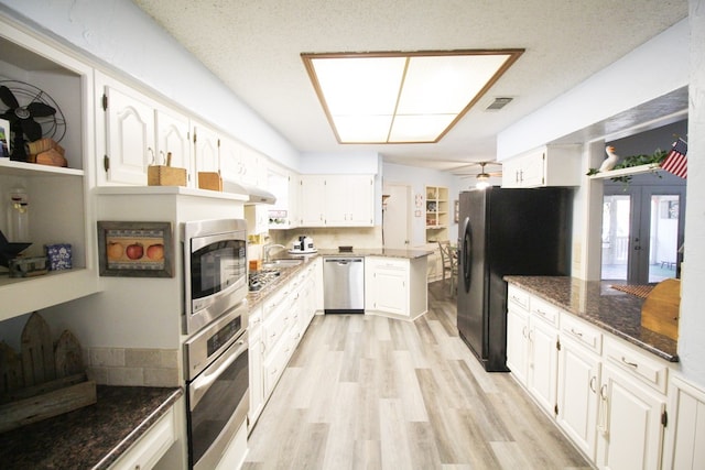 kitchen featuring light hardwood / wood-style floors, dark stone counters, white cabinetry, and stainless steel appliances