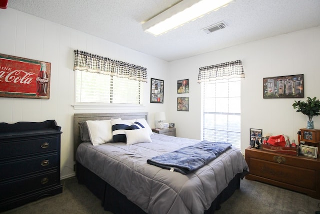 carpeted bedroom with multiple windows and a textured ceiling