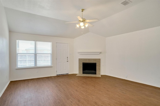 unfurnished living room with wood finished floors, visible vents, lofted ceiling, ceiling fan, and a tile fireplace