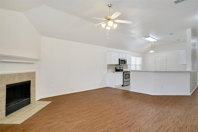 unfurnished living room featuring baseboards, light wood-style flooring, a fireplace, ceiling fan, and vaulted ceiling