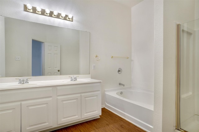 bathroom with wood finished floors, a shower with shower door, and a sink