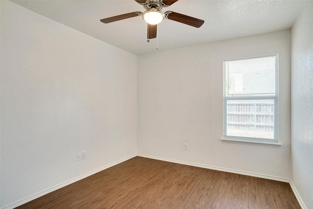 spare room featuring ceiling fan, baseboards, and wood finished floors