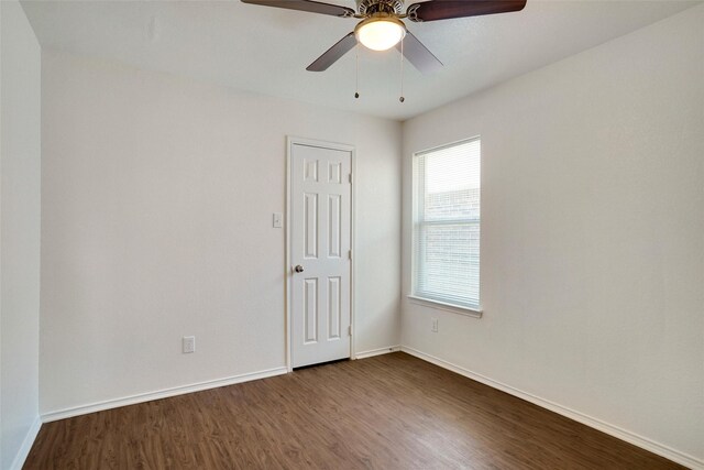 empty room with baseboards, dark wood-type flooring, and ceiling fan