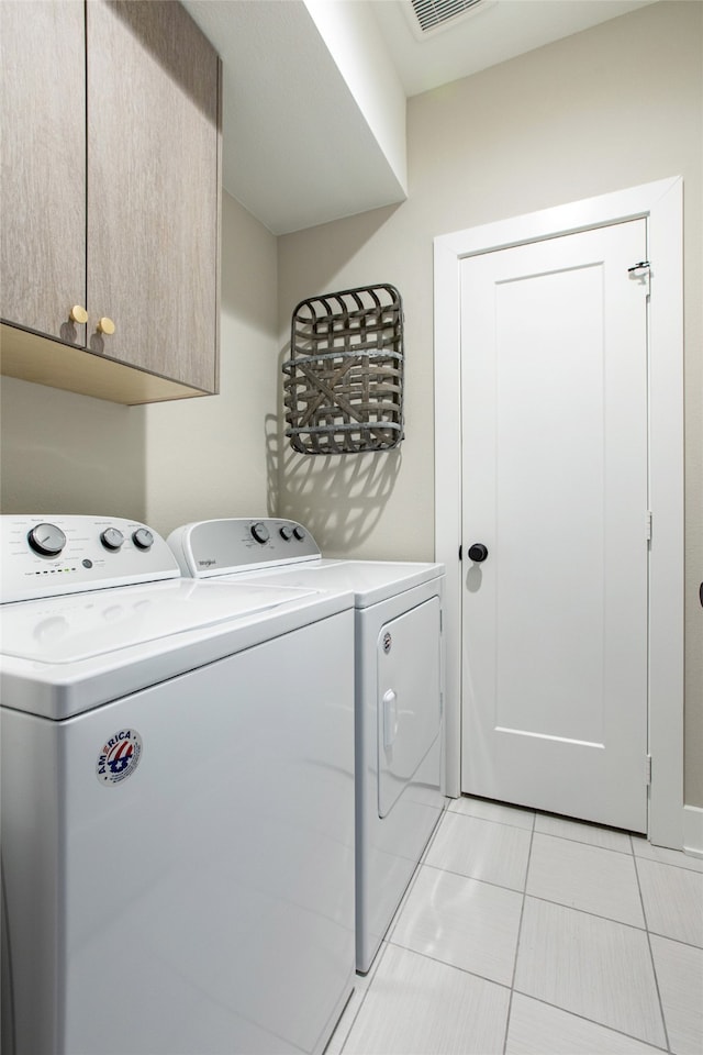 laundry area with light tile patterned floors, independent washer and dryer, and cabinets