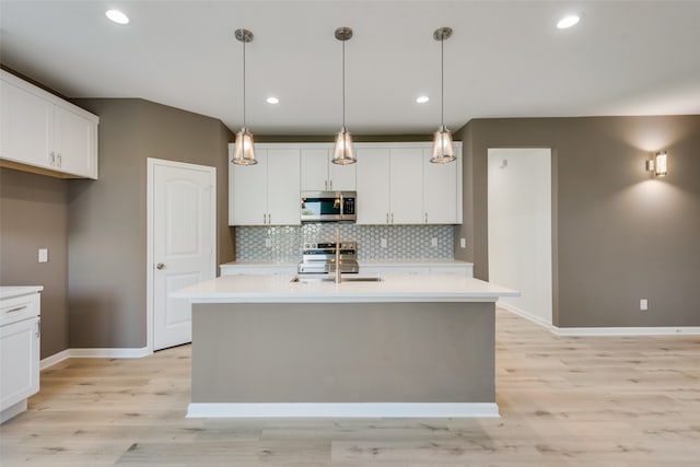 kitchen with hanging light fixtures, stainless steel appliances, backsplash, and white cabinets