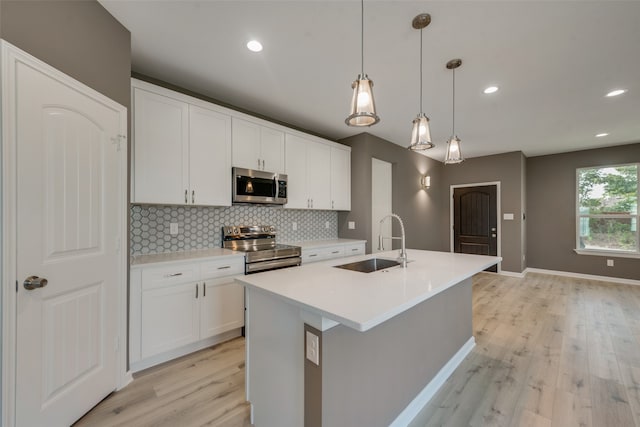 kitchen with tasteful backsplash, stainless steel appliances, white cabinets, sink, and light hardwood / wood-style floors