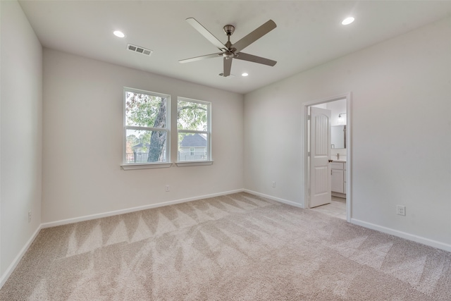 unfurnished bedroom with ensuite bath, ceiling fan, and light colored carpet