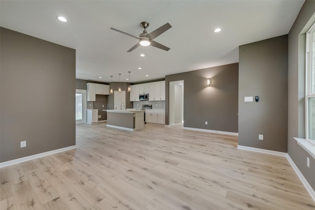 unfurnished living room featuring light hardwood / wood-style flooring, sink, and ceiling fan