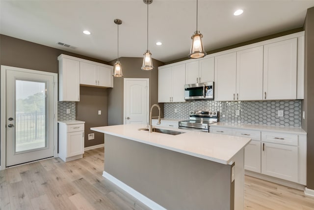 kitchen with appliances with stainless steel finishes, tasteful backsplash, sink, light wood-type flooring, and white cabinetry