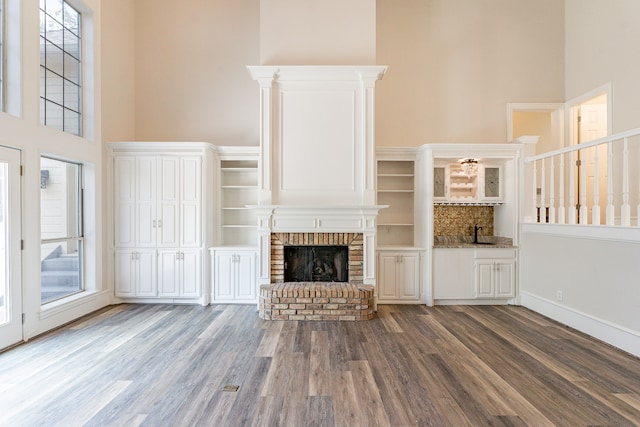 unfurnished living room with a high ceiling, a fireplace, dark hardwood / wood-style floors, and ornamental molding