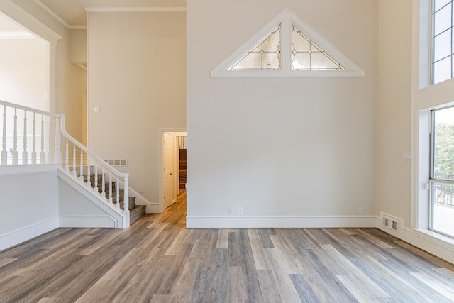 unfurnished living room featuring an inviting chandelier, a fireplace, crown molding, and dark wood-type flooring