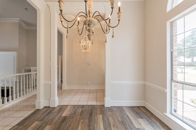 entryway featuring wood-type flooring, ornamental molding, and a towering ceiling