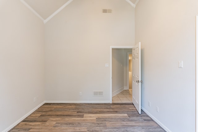 unfurnished bedroom with high vaulted ceiling, crown molding, and dark hardwood / wood-style flooring