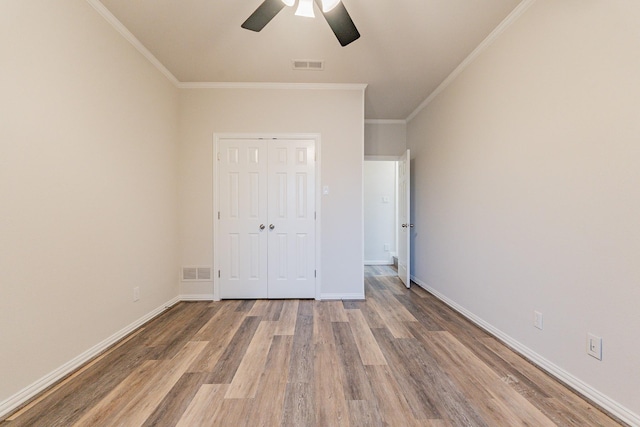 unfurnished bedroom with ceiling fan, ornamental molding, hardwood / wood-style floors, and a closet