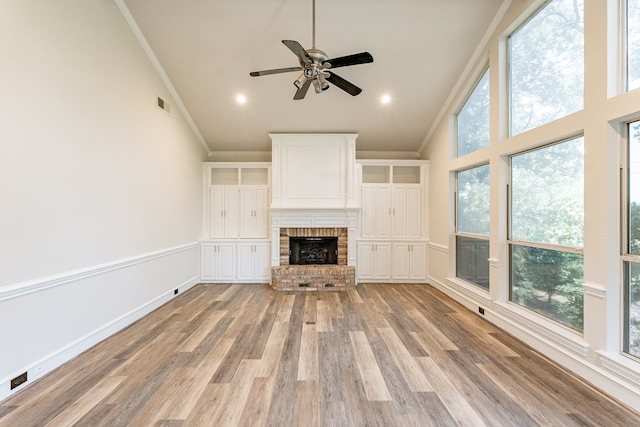 unfurnished living room with ornamental molding, ceiling fan, light hardwood / wood-style floors, a fireplace, and high vaulted ceiling