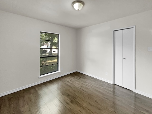 unfurnished bedroom featuring dark wood-type flooring and a closet