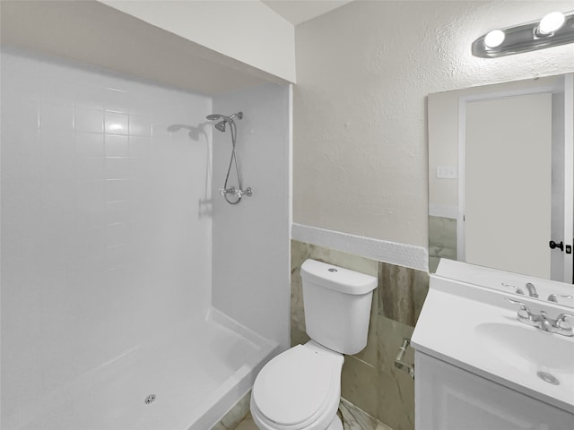 bathroom with tiled shower, toilet, and vanity