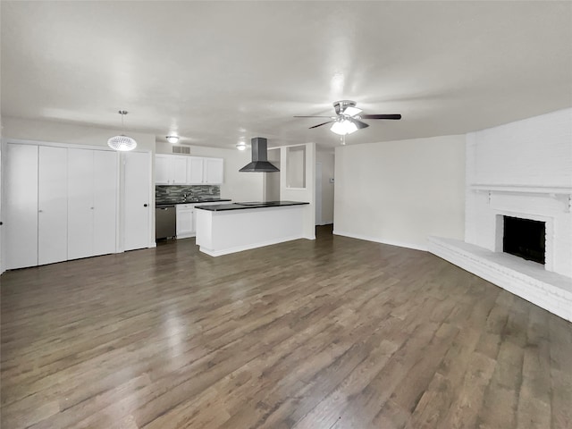 unfurnished living room with hardwood / wood-style flooring, a brick fireplace, and ceiling fan