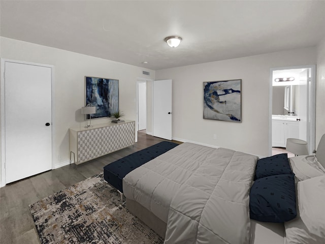 bedroom featuring ensuite bathroom and dark hardwood / wood-style floors