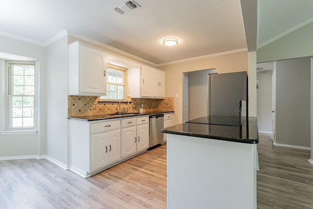 kitchen with white cabinetry, stainless steel appliances, light hardwood / wood-style floors, decorative backsplash, and sink