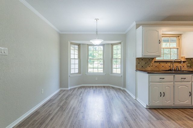 unfurnished dining area with sink, crown molding, and light wood-type flooring