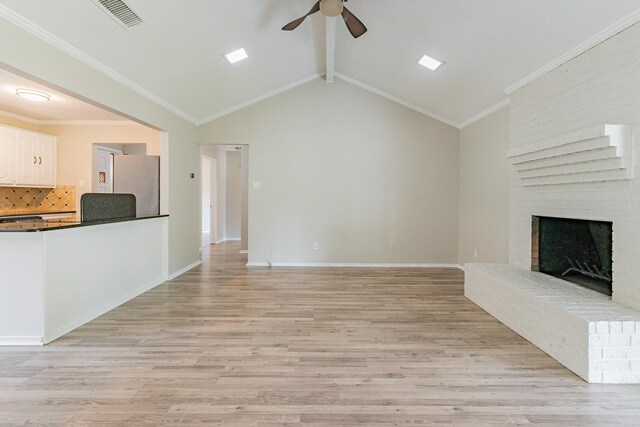 unfurnished living room with a fireplace, light hardwood / wood-style floors, vaulted ceiling with beams, and ceiling fan