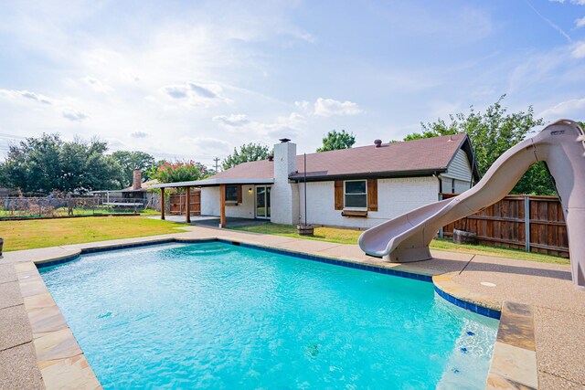 view of swimming pool with a water slide, a yard, and a patio area