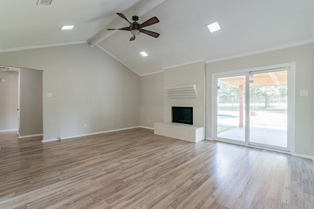 unfurnished living room with light wood-type flooring, ceiling fan, brick wall, a fireplace, and lofted ceiling with beams