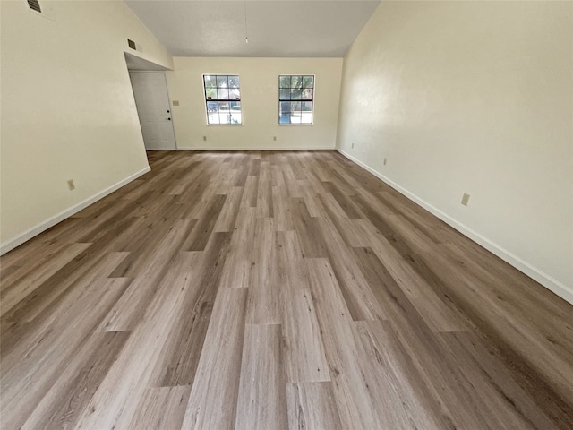 unfurnished room with lofted ceiling and light hardwood / wood-style floors