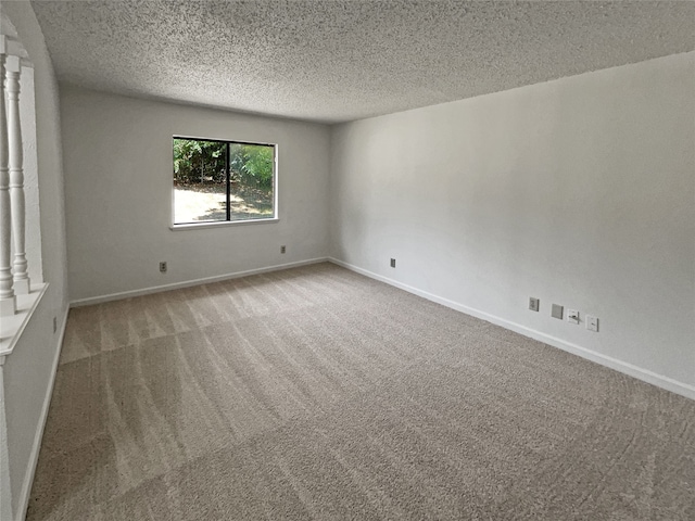 spare room featuring decorative columns, carpet floors, and a textured ceiling