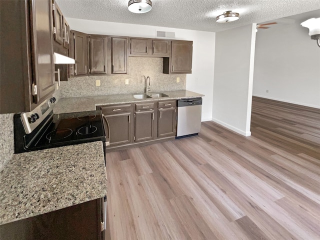 kitchen featuring ventilation hood, light wood-type flooring, sink, appliances with stainless steel finishes, and a textured ceiling