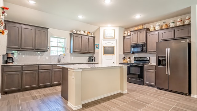 kitchen with light stone countertops, dark brown cabinetry, a center island, and stainless steel appliances