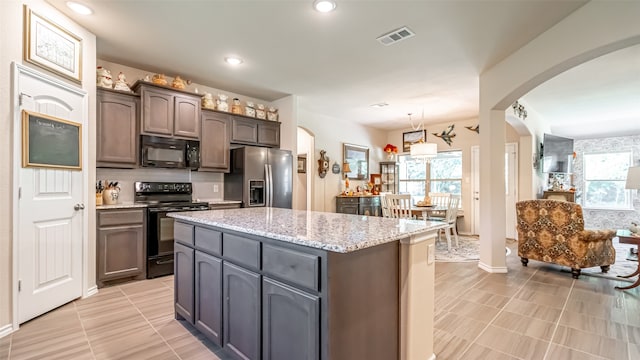 kitchen with a kitchen island, black appliances, dark brown cabinets, and a healthy amount of sunlight