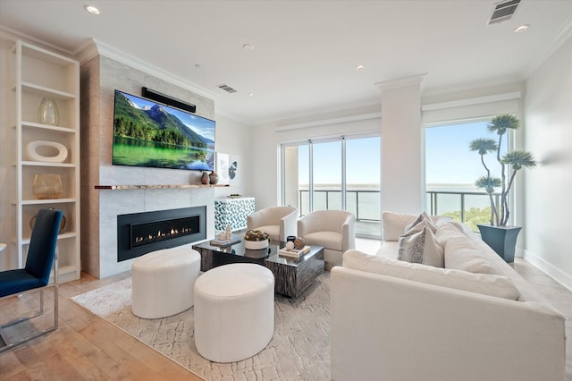 living room with ornamental molding, a fireplace, and light hardwood / wood-style floors