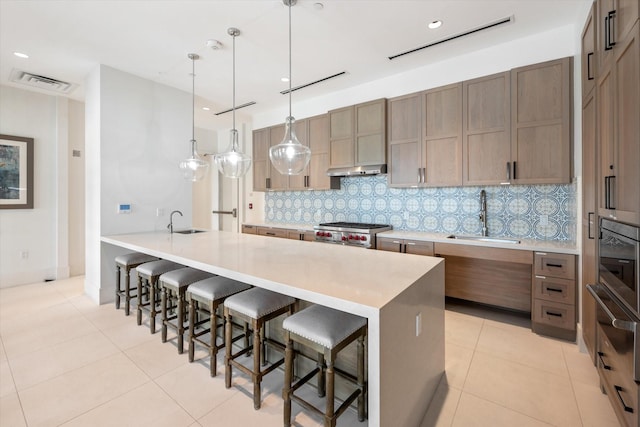 kitchen featuring a breakfast bar, sink, light tile patterned floors, pendant lighting, and stove