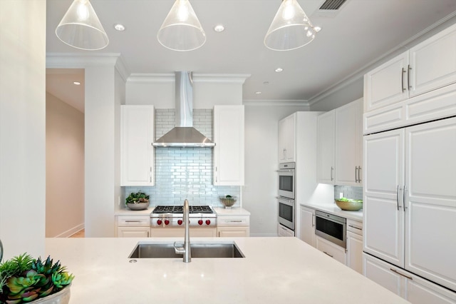 kitchen featuring sink, white cabinetry, built in appliances, decorative light fixtures, and wall chimney exhaust hood