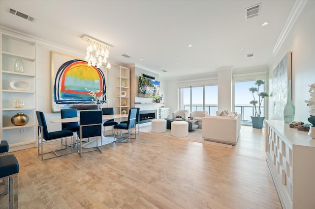 living room featuring a notable chandelier, ornamental molding, and light wood-type flooring