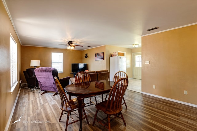 dining space featuring wood-type flooring, ceiling fan, and crown molding