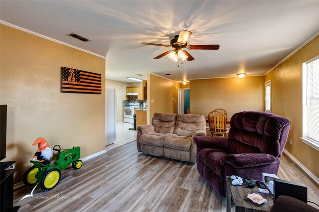 living room with crown molding, ceiling fan, a wealth of natural light, and light tile patterned floors