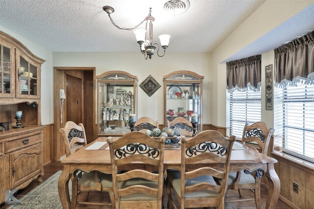 dining room with hardwood / wood-style flooring, a textured ceiling, and an inviting chandelier