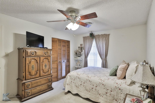 carpeted bedroom with a textured ceiling, a closet, and ceiling fan