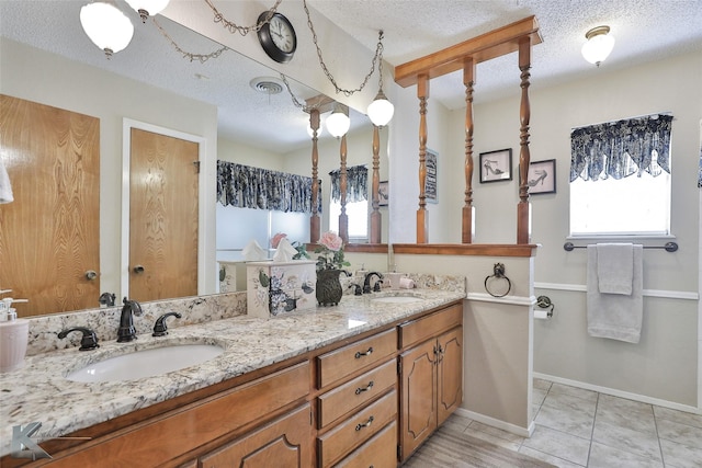 bathroom with tile patterned flooring, dual vanity, and a textured ceiling