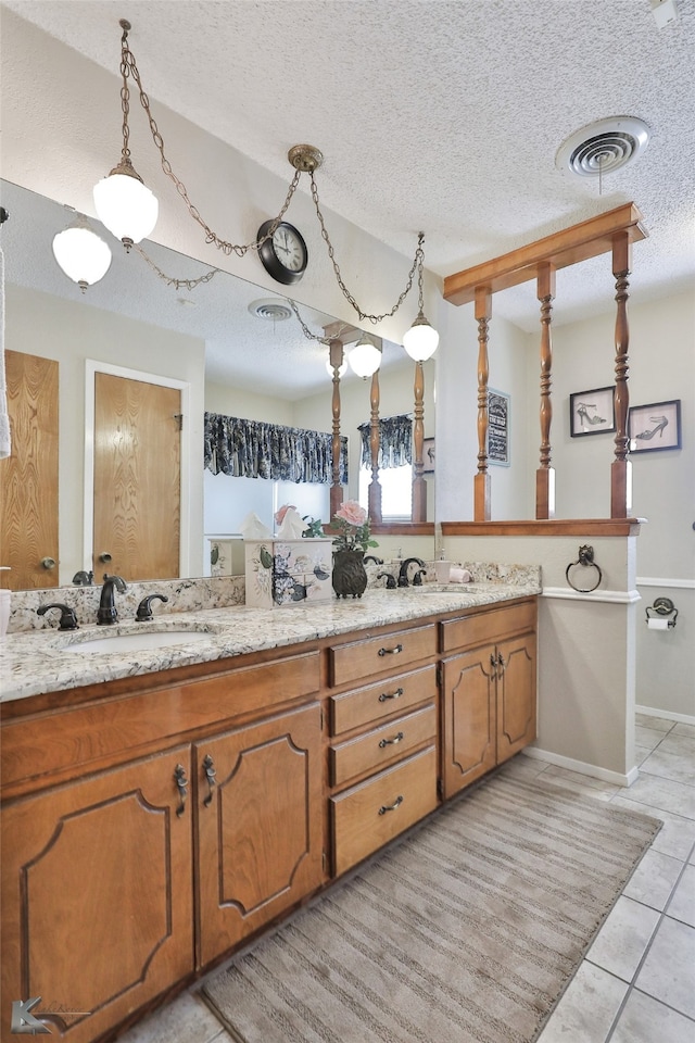 bathroom with dual vanity, tile patterned flooring, and a textured ceiling