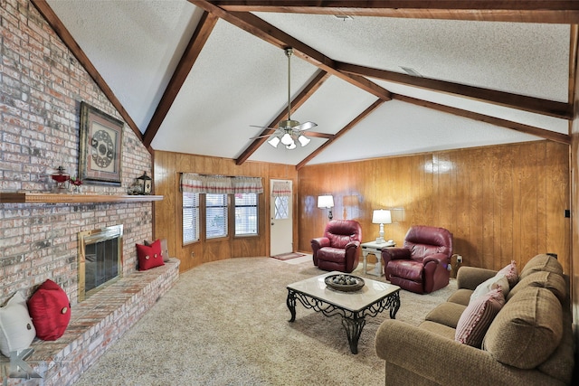 carpeted living room with wooden walls, a textured ceiling, ceiling fan, a brick fireplace, and lofted ceiling with beams